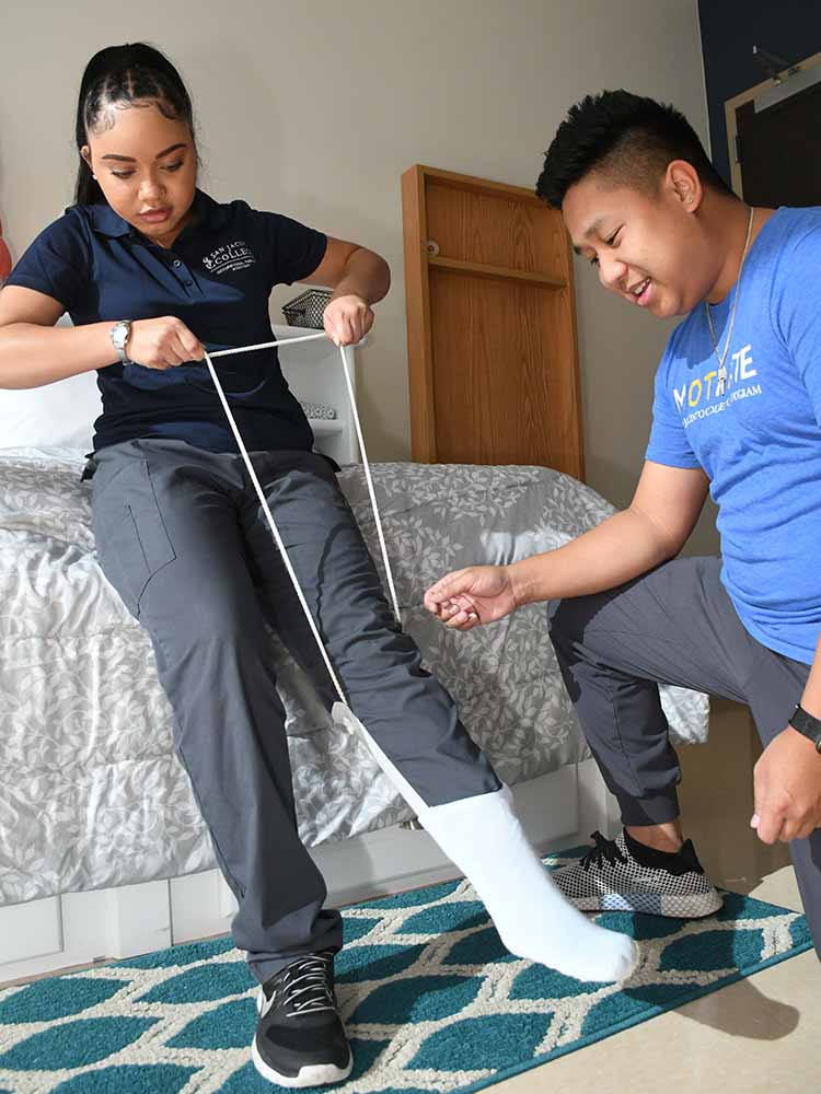 occupational therapy assistant helping patient pull brace on ankle up for stability
